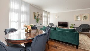 A modern living room with a round glass table, green sofa, and a flat-screen TV. - Beautiful apartment in the heart of Mayfair (London)