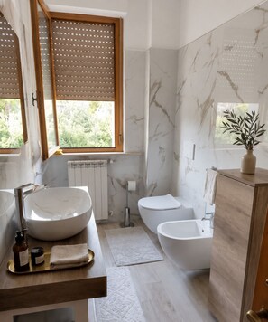 A modern bathroom with a large vessel sink, a freestanding bathtub, a toilet, and a wooden vanity.