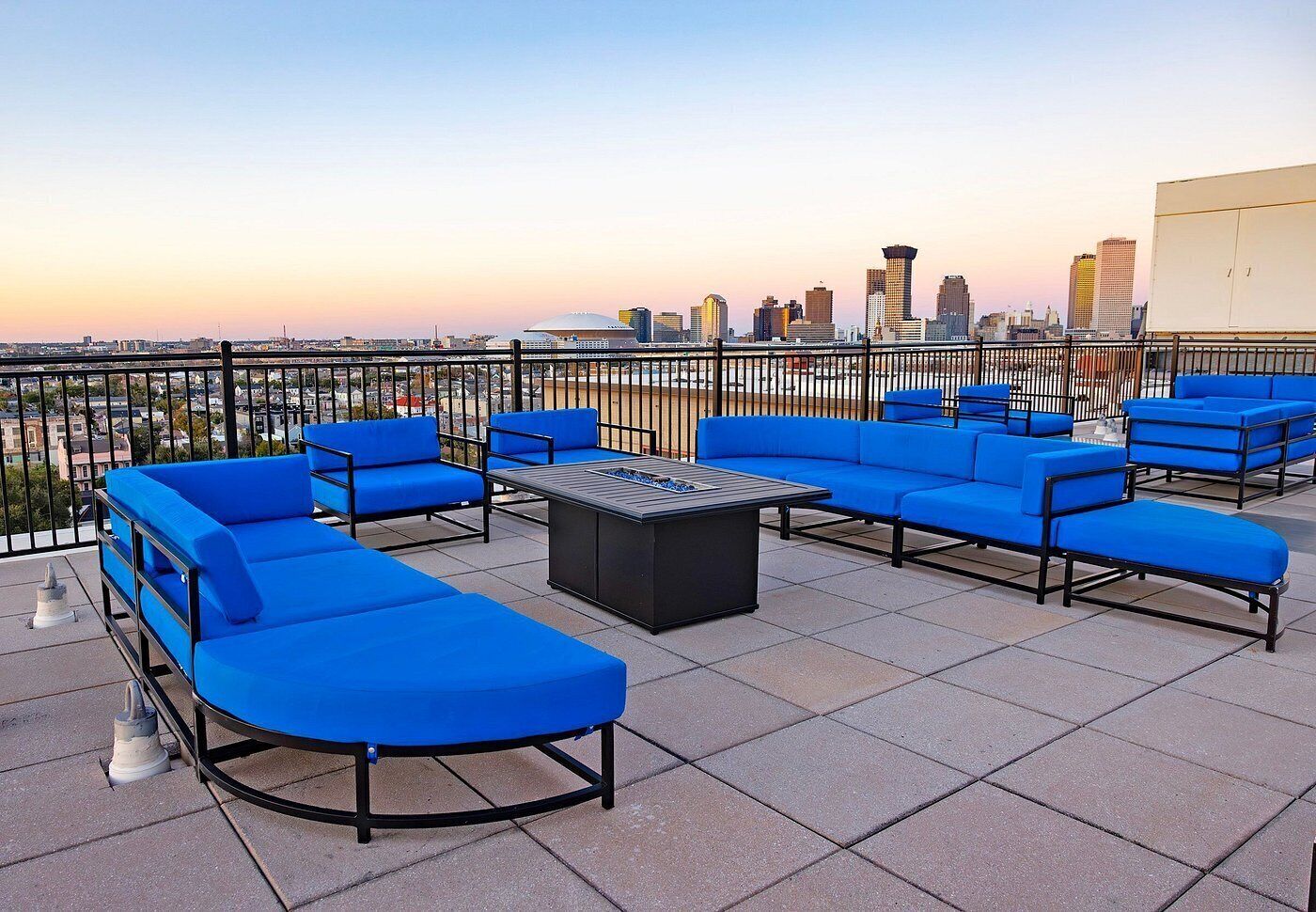 A rooftop terrace with blue seating, a fire pit, and a city skyline view.