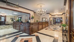 A lobby with a reception desk, chandeliers, and a checkered floor.