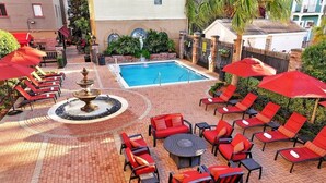 A poolside area with lounge chairs, a fountain, and a brick patio.