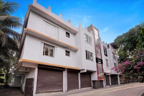 A multi-story building with closed shutters, a sign with Chinese characters, and a palm tree in the background. - Collection O Calangute Circle (Calangute)