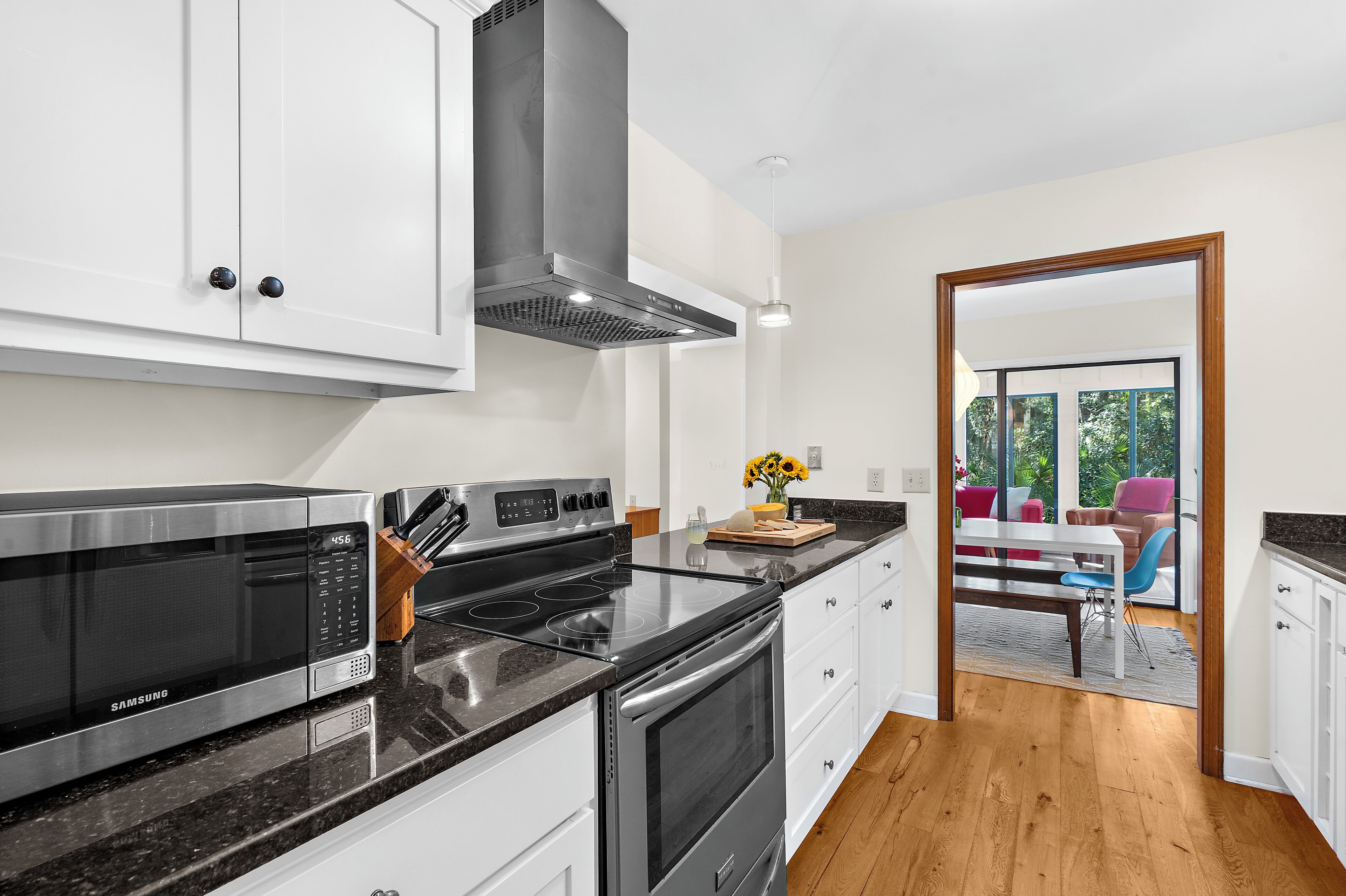 Una cocina moderna con electrodomésticos de acero inoxidable, armarios blancos y suelo de madera.