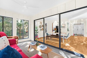 Ein modernes Wohnzimmer mit einem roten Sofa, einem Holztisch und einer Glastür zum Essbereich.