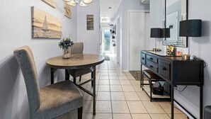 Una cocina moderna con una mesa de comedor redonda, una silla, un armario negro con espejo y una lámpara colgante.