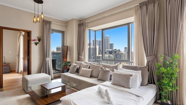A modern hotel room with a large bed, a sofa, a glass coffee table, and a view of the city skyline. - Relaxing 1bedroom mins drive to Burj Khalifa (Dubai)