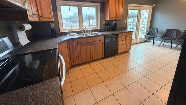 A kitchen with wooden cabinets, a dishwasher, a sink, and a window.