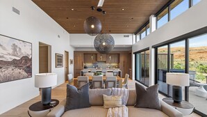 Un salon moderne avec un canapé, des lampes et un coin repas, la cuisine étant visible à l’arrière-plan.