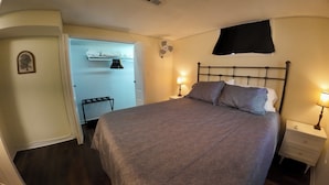 Une chambre à coucher comprenant un lit, des lampes de chevet, une armoire et un ventilateur fixé au mur.