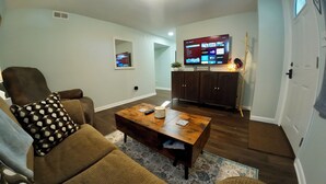 Una sala de estar con sofá, mesa de centro, televisor y armarios de madera.