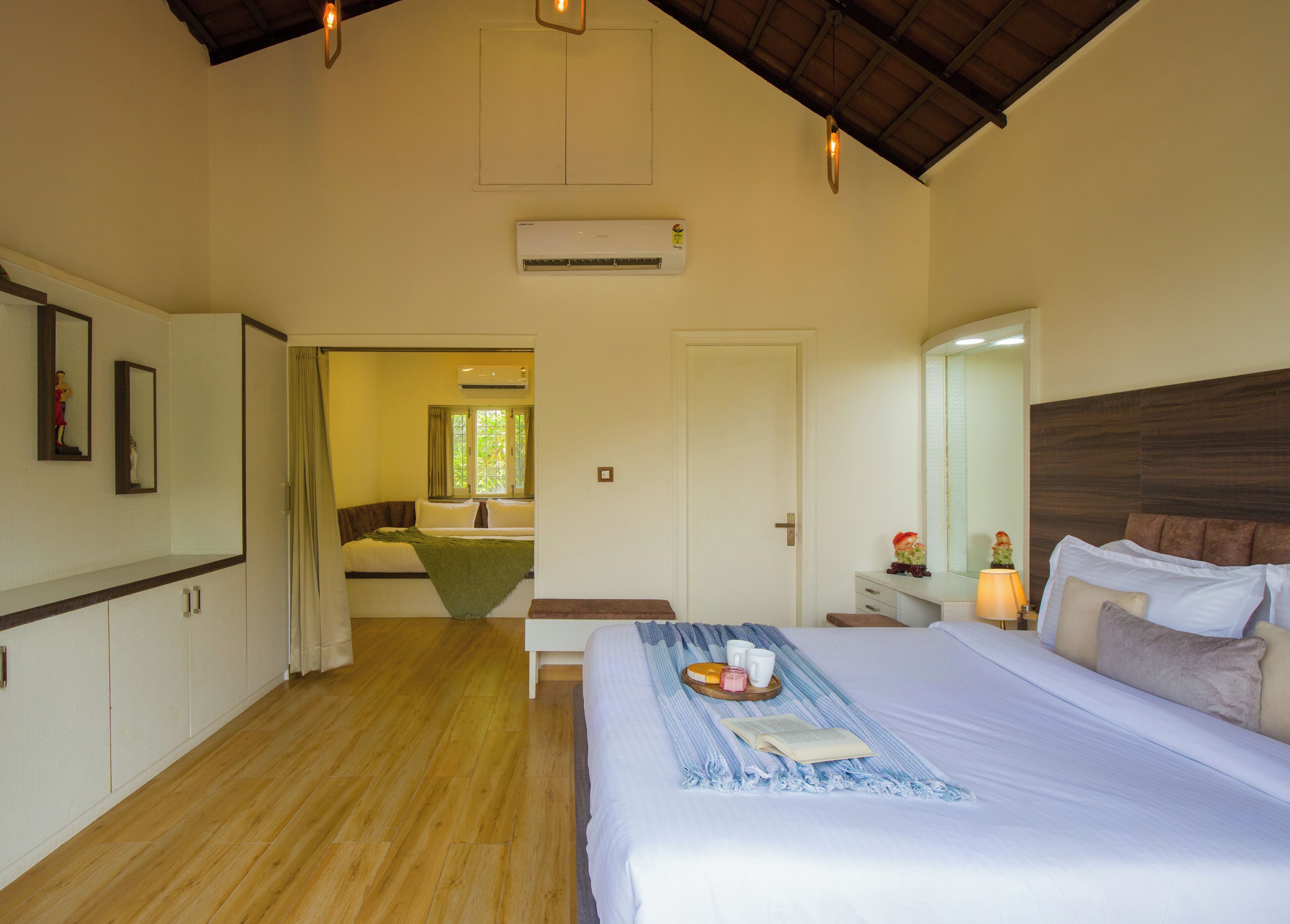 A hotel room with a bed, bedside table, lamp, and a view of a bathroom.