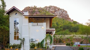 A modern house with a stone staircase, a view of a mountain, and a white fence. - Alaya Stays Ramgarh Colonial 2BHK Villa (Jamwa Ramgarh)