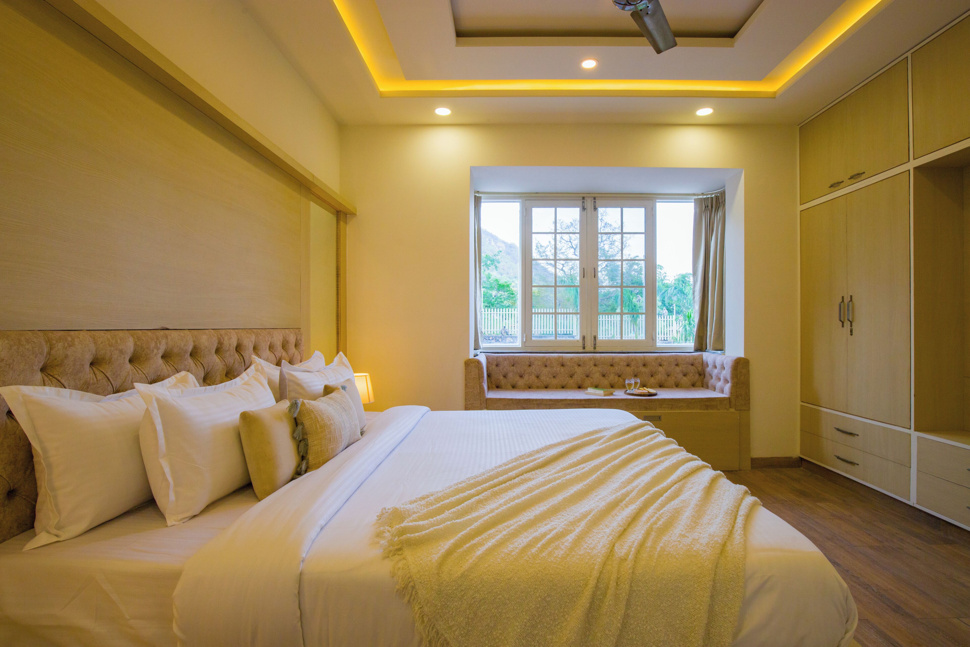 A bedroom with a large bed, a window with a view, and built-in wardrobe.