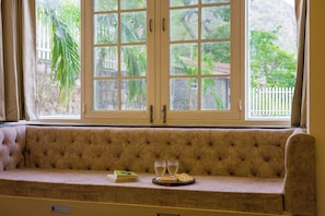 A cushioned bench with a view of greenery and a white fence outside. - Alaya Stays Ramgarh Colonial 2BHK Villa (Jamwa Ramgarh)