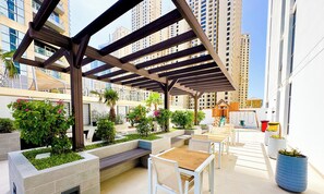 An outdoor patio area with seating, planters, and a pergola structure. - LUX Contemporary Suite Marina View 5 (Dubai)