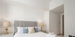 A modern hotel room with a large bed, two bedside tables with lamps, and a neutral color scheme. - LUX Contemporary Suite Marina View 5 (Dubai)