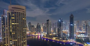 A nighttime cityscape with high-rise buildings, a river, and illuminated pathways. - LUX Contemporary Suite Marina View 5 (Dubai)