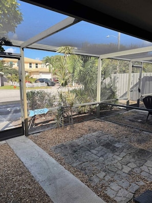 A covered outdoor area with a sign indicating a pool, surrounded by plants and a paved walkway. - Cozy Haven Oasis: Pool| Los Olas |Wilton Manors (Wilton Manors)