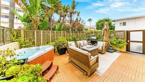A patio with a hot tub, outdoor seating, and lush greenery. - Amazing Location, Across from the Beach W/Jacuzzi! (San Diego)