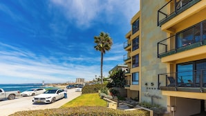 A multi-story building with balconies, a parking lot, and a palm tree. - Amazing Location, Across from the Beach W/Jacuzzi! (San Diego)