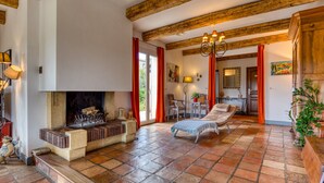 A spacious living room with a fireplace, a lounge chair, and a dining area. - Languedoc Villa with Pool and Mountain View (Pailhès)