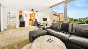 Ein modernes Wohnzimmer mit einer Ledersofa, einem runden Couchtisch und einem Essbereich mit einer Küche im Hintergrund.