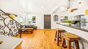 Een keuken met houten vloeren, een eethoek met een bank en een trap met een decoratieve leuning.