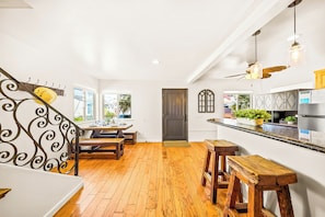 A kitchen with wooden flooring, a dining area with a bench, and a staircase with a decorative railing. - Great Reviews, Large Rooftop Deck W/Parking, Stunning (San Diego)