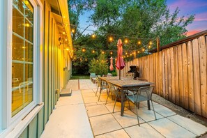 Eine Terrasse mit Tisch und Stühlen, Lichterketten und einem Holzzaun.