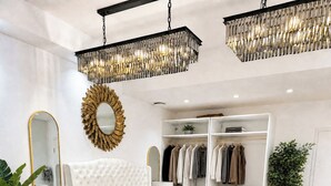 A modern bedroom with a large bed, a walk-in closet, and a chandelier.