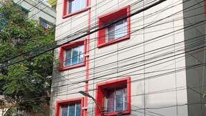 Un bâtiment doté de nombreuses fenêtres, dont certaines ont des cadres rouges, et une enseigne indiquant « AG STAR RESTAURANT » au rez-de-chaussée.