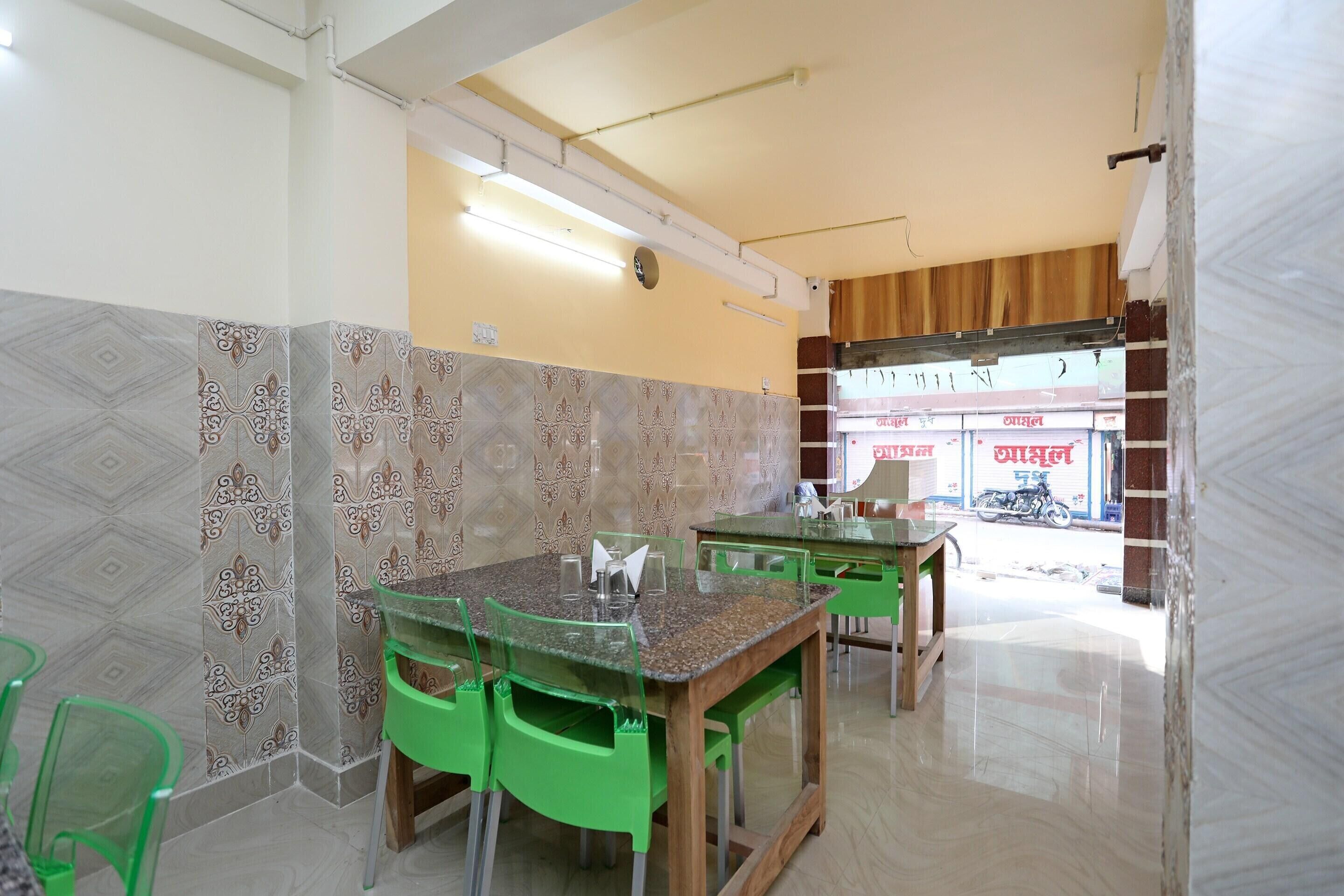 A restaurant with green chairs and tables, patterned walls, and a view of the street.
