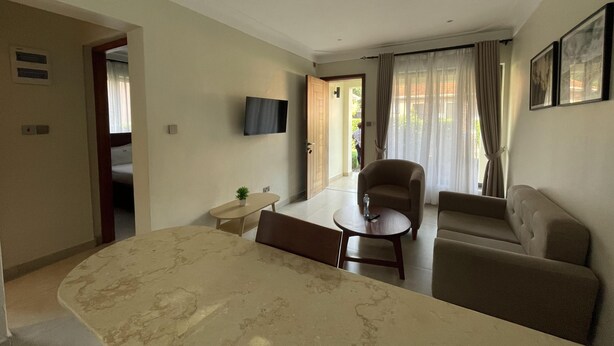 Une chambre d’hôtel comprenant un lit, un bureau, une chaise, un canapé, une télévision et une porte donnant sur un balcon.