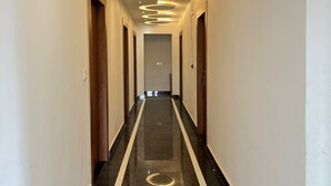 A hallway with a reflective black floor, circular ceiling lights, and wooden doors. - Hotel Girraj Stay Inn  (Mathura)