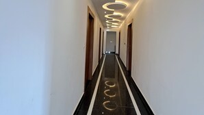 A hallway with circular ceiling lights, a reflective floor, and wooden doors. - Hotel Girraj Stay Inn  (Mathura)