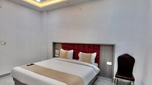 A modern bedroom with a bed, a chair, a ceiling fan, and recessed lighting. - Hotel Girraj Stay Inn  (Mathura)