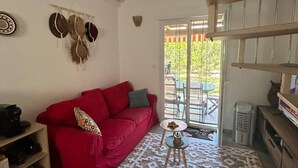 A living room with a red sofa, a patterned rug, a small table, and a staircase. - Mini Villa "Mon Rêve Corse" Seaside in Residence with Swimming Pool (Cervione)