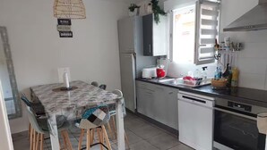 A kitchen with a dining table, chairs, a refrigerator, a sink, and a stove. - Mini Villa "Mon Rêve Corse" Seaside in Residence with Swimming Pool (Cervione)