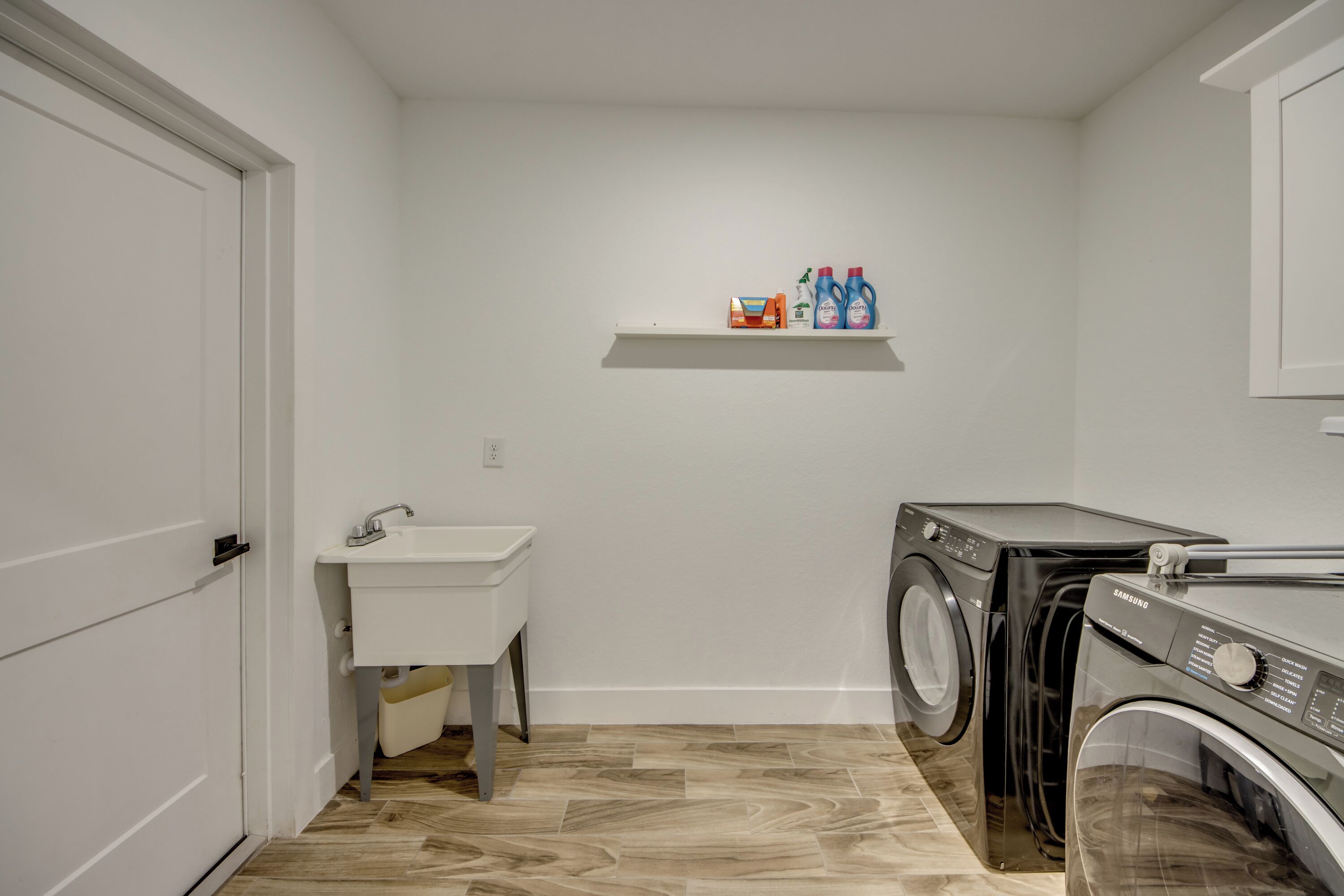 A laundry room with a washing machine, dryer, and a small sink.