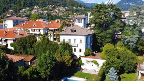 Et boligområde med en swimmingpool, omgivet af frodigt grønt og huse.