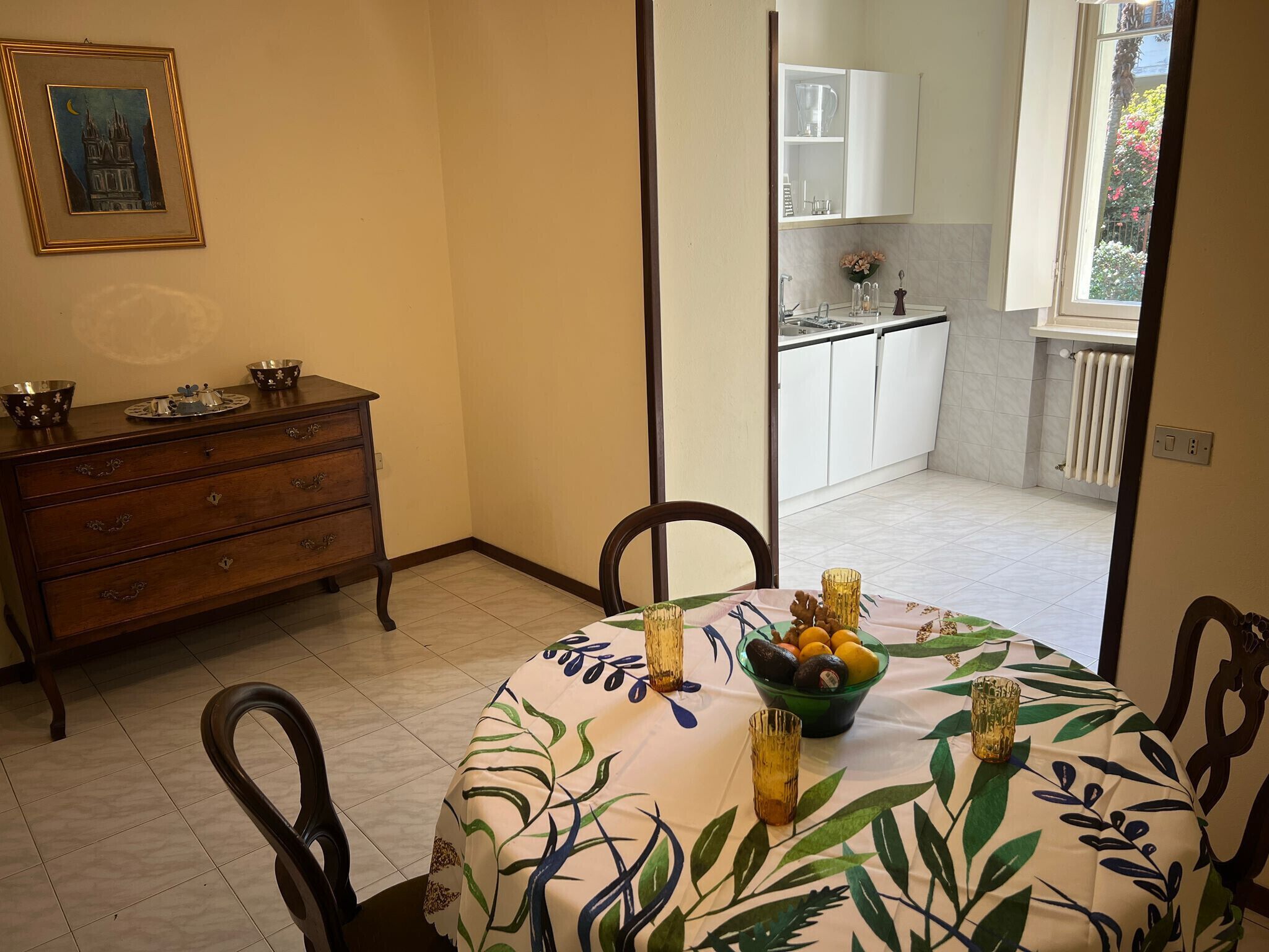 A dining area with a table set for two, a wooden dresser, and a view into the kitchen.