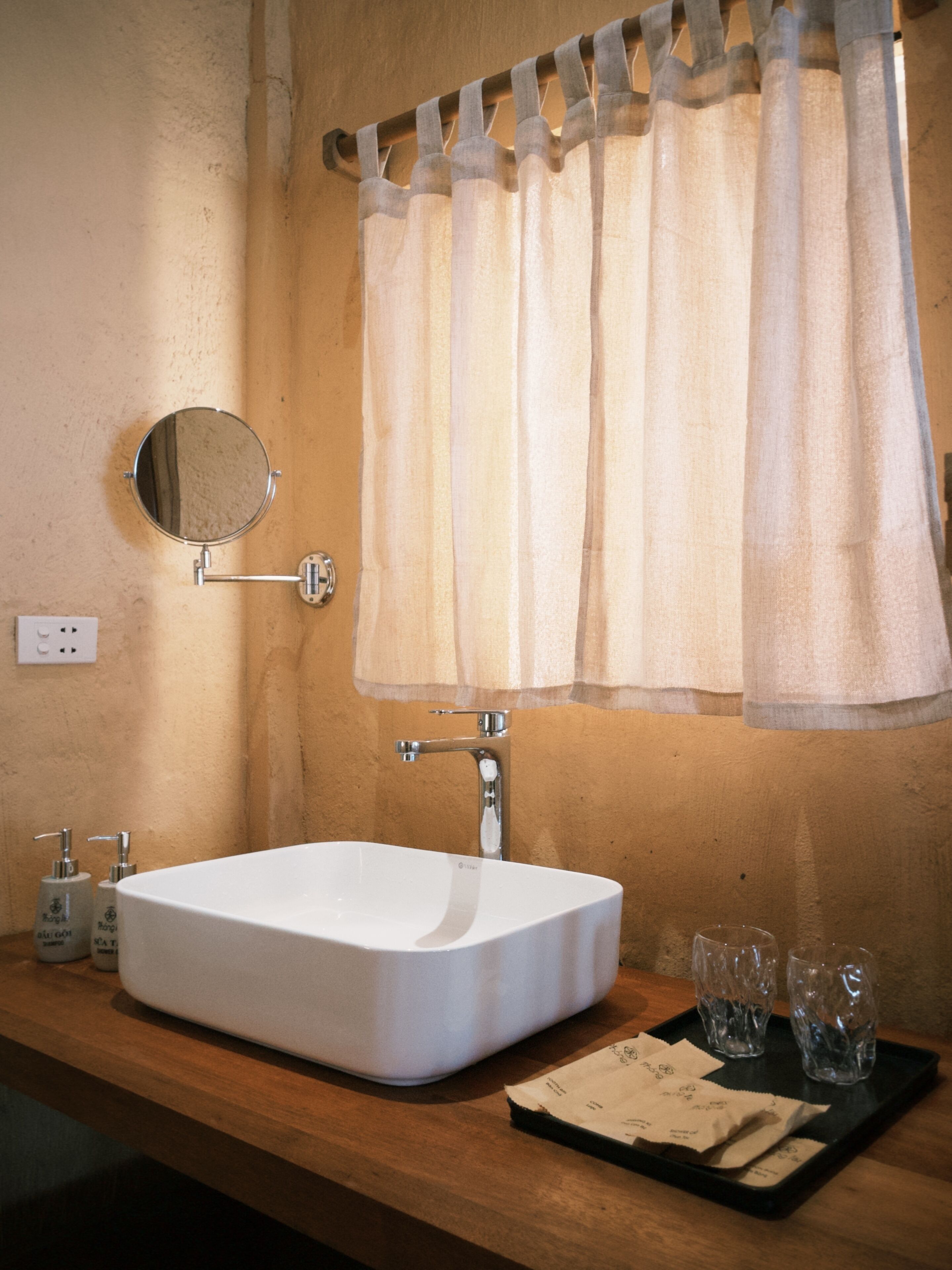 A bathroom with a white sink, a mirror, a towel rack with a towel, a faucet, and two bottles of shampoo.