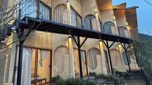 Un edificio de varios pisos con fachada de madera, grandes ventanales arqueados y un balcón cubierto.
