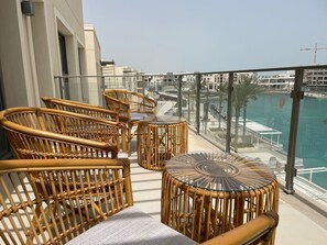 A balcony with wicker furniture, a glass table, and a view of a marina. - Chalet 3 Bedrooms LR - 404 in Marassi (El Alamein)