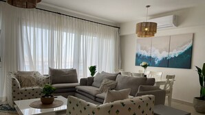 Ein Wohnzimmer mit einer Sofagarnitur, einem Couchtisch und einem Essbereich mit Stühlen.