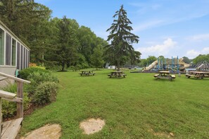 A grassy park area with picnic tables and a playground. - Juniper Presents: Chalet #74 Walk to Pool, Courts & Resort Amenities (Stevensville)