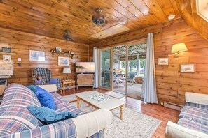 Een gezellig chaletinterieur met houten plafond, een zithoek, een televisie en een eettafel.
