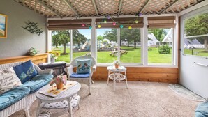 Een gezellige kamer met uitzicht op een speeltuin, rieten meubels en een plafondventilator.