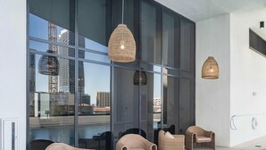 Een moderne buitenruimte met rieten stoelen en hangende rieten lampen, met uitzicht op een stadsbeeld.