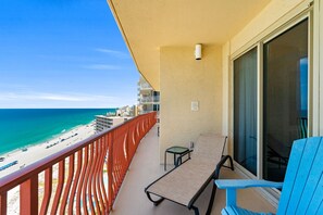 Ein Balkon mit Blick auf den Strand, inklusive Tisch, Stühlen und Geländer.